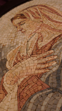 Intricate mosaic artwork depicting a serene figure in warm tones — handcrafted tiles create a textured visual experience