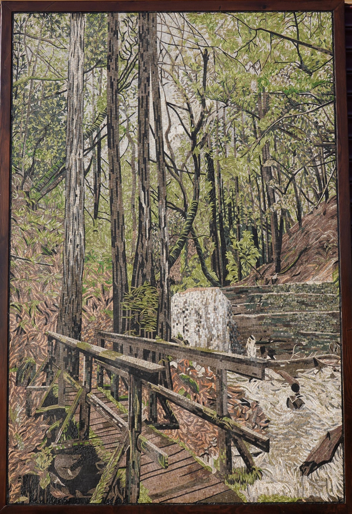Intricate tapestry artwork depicting a serene forest scene with vibrant greenery and a wooden bridge over flowing water