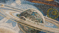 Vivid mosaic artwork depicting a planet with rings surrounded by celestial bodies — intricate tiles showcasing a cosmic scene
