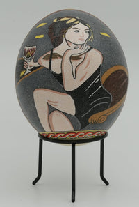 Artistic decorative egg featuring a woman in a black dress, intricately hand-painted with vibrant colors and fine details