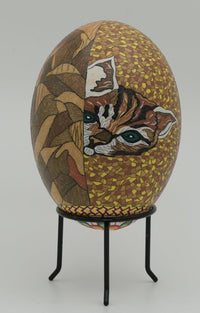 Intricate decorative egg featuring a hand-painted cat design with vibrant colors and detailed textures on a sturdy stand