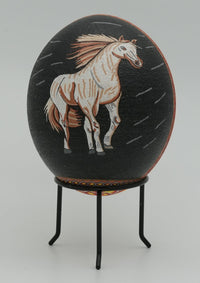 Hand-painted decorative egg featuring a white horse against a black background — intricate details with a glossy finish