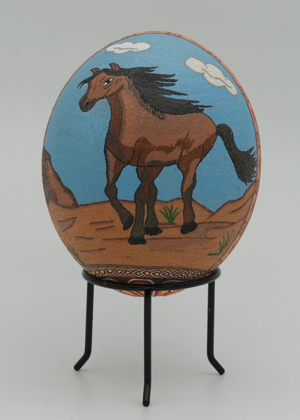 Hand-painted decorative egg featuring a brown horse on a blue background — vibrant artwork set against a neutral stand