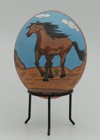 Hand-painted decorative egg featuring a brown horse on a blue background — vibrant artwork set against a neutral stand