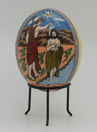 Intricately designed decorative egg featuring a biblical scene with vibrant colors and fine detailing on a stand.