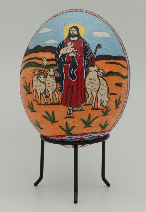 Hand-painted decorative egg featuring a shepherd in vibrant colors surrounded by sheep — intricate design on a smooth surface