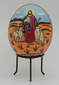 Hand-painted decorative egg featuring a shepherd in vibrant colors surrounded by sheep — intricate design on a smooth surface