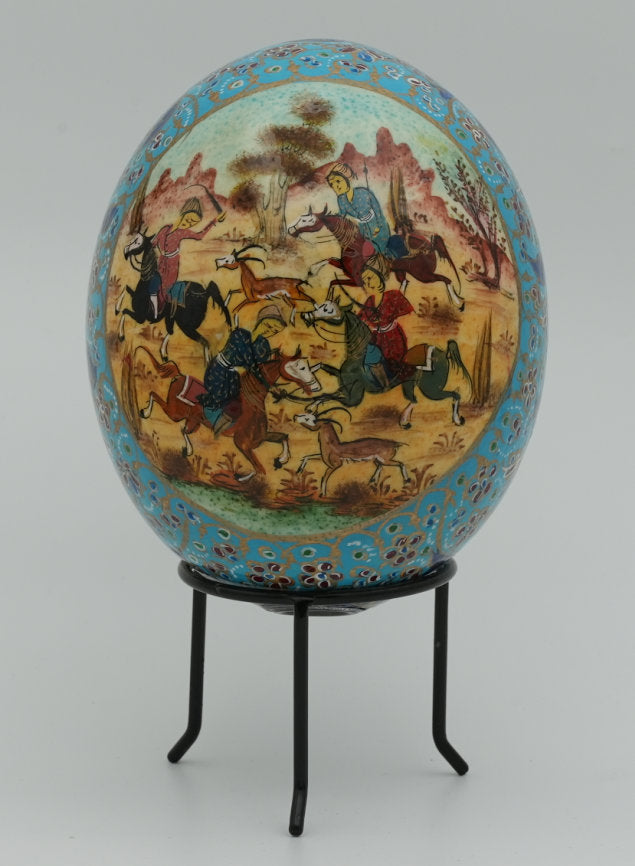 Intricately painted decorative egg featuring a vibrant scene of horsemen in a pastoral landscape, set on a sleek black stand