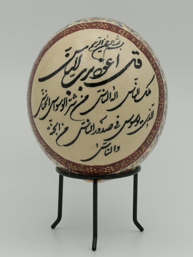 Intricately designed decorative egg featuring traditional calligraphy on a cream background — a unique piece of art displayed on a stand.