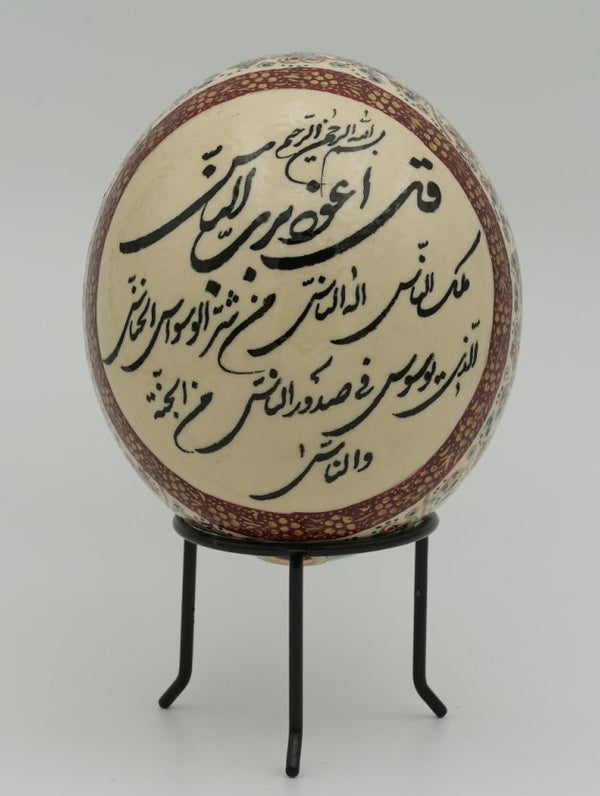 Intricately designed decorative egg featuring traditional calligraphy on a cream background — a unique piece of art displayed on a stand.