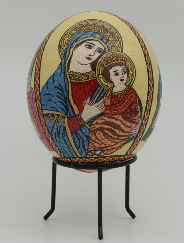 Intricately painted decorative egg featuring a Madonna and child design — vibrant colors on a smooth surface with ornate details.