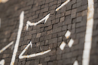 Intricate mosaic artwork featuring geometric patterns in black and white — showcasing a textured surface with depth.