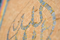 Intricate mosaic wall art featuring a shimmering gold and blue design against a textured beige background — a stunning decorative piece.