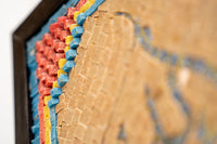 Intricate wall art featuring vibrant blue, red, and yellow geometric patterns on a textured wooden background.