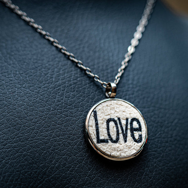 Charming pendant necklace featuring a round silver base with a textured white inlay displaying the word 'Love'