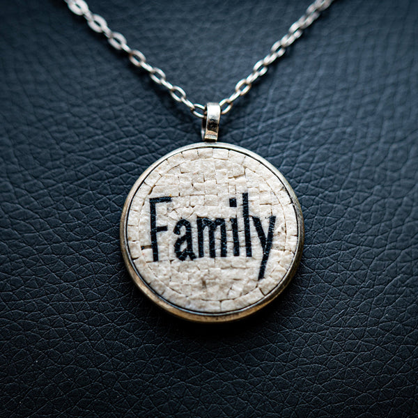 Circular pendant necklace featuring a textured white background with the word 'Family' embossed in black — a meaningful piece of jewellery.