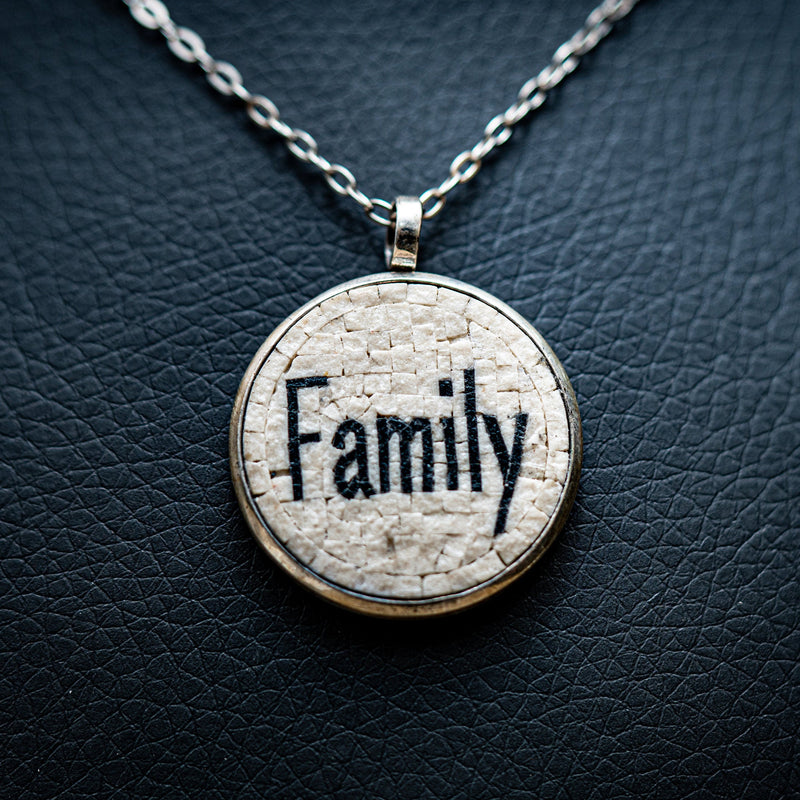 Circular pendant necklace featuring a textured white background with the word 'Family' embossed in black — a meaningful piece of jewellery.