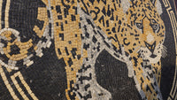 Intricate mosaic art featuring a leopard design in black, gold, and white stone tiles with a textured surface.