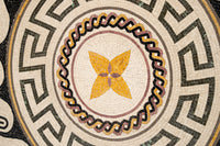 Intricate mosaic design featuring a yellow floral pattern surrounded by geometric black and white tiles — a stunning artistic display.