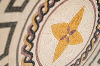 Intricate mosaic tile design featuring a vibrant yellow floral pattern surrounded by dark geometric borders
