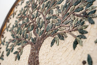 Intricate mosaic wall art featuring a tree design with green and brown tiles set against a textured cream background