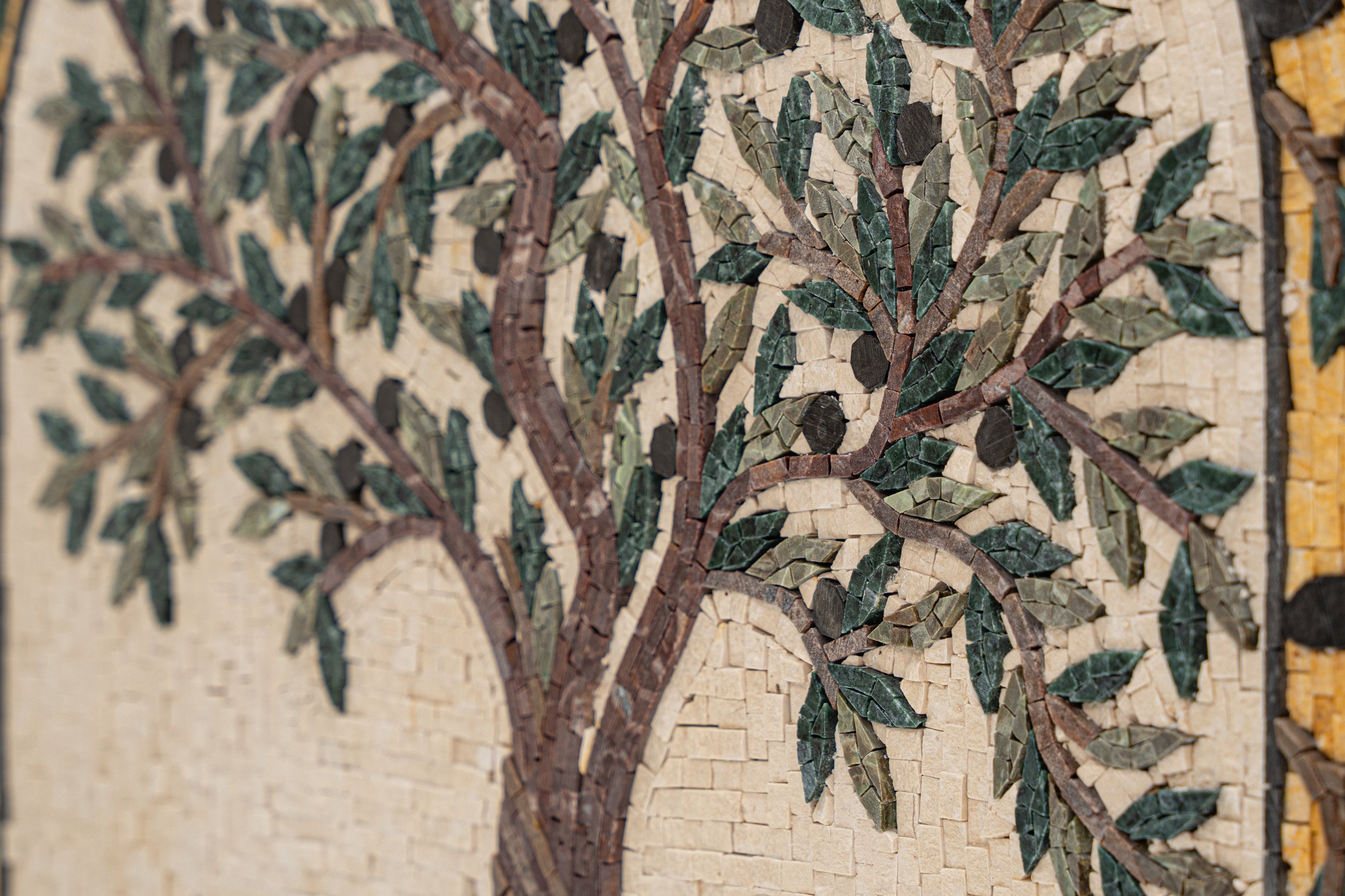 Intricate mosaic art featuring a tree design with green leaves and a textured beige background — a stunning blend of craftsmanship.