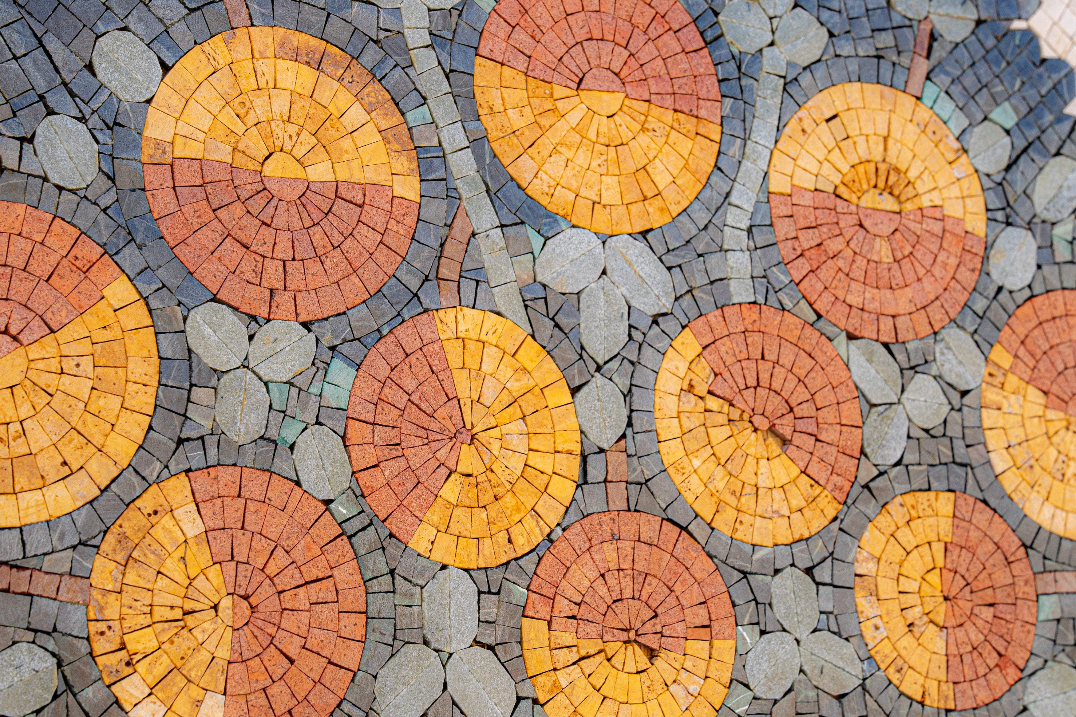 Vibrant mosaic tiles in circular patterns featuring earthy tones of orange and brown — a decorative flooring element with texture.