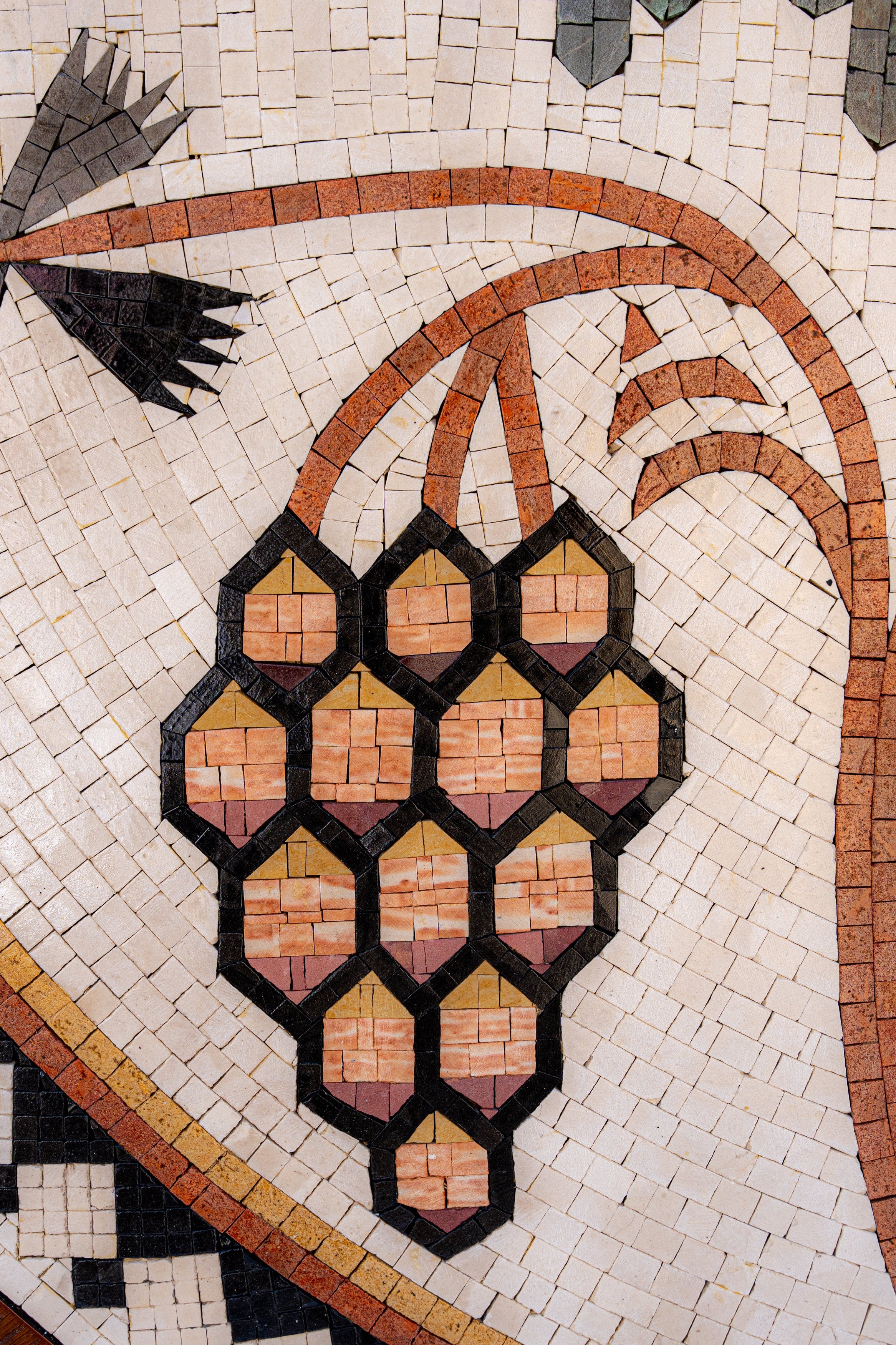 Intricate mosaic design featuring a cluster of grapes in earthy tones—crafted with detailed hexagonal tiles.