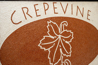 Intricate mosaic design featuring a grapevine motif in earthy tones — a decorative sign for Crepevine restaurant.