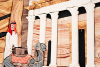Intricate wooden wall art depicting a man on a camel in front of classical columns — rich textures and vibrant colors