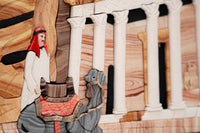 Intricate artisan-crafted scene depicting a man with a red headdress beside a camel — detailed stonework showcasing ancient architecture.