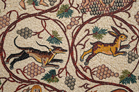 Intricate mosaic artwork depicting a running greyhound and a leaping hare surrounded by grapevines and foliage.