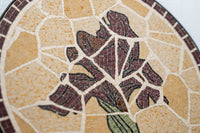 Intricate mosaic wall art featuring a purple iris design on a textured beige background — a stunning blend of craftsmanship and color.