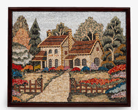 Intricate mosaic artwork depicting a charming cottage surrounded by vibrant flowers and lush trees — framed in rich wood.