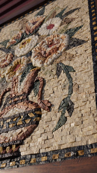 Intricate floral mosaic art crafted from colorful stone pieces — featuring roses in a decorative vase with detailed leaves.