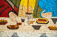 Vibrant mosaic artwork featuring colorful hands preparing dishes on a textured stone surface — intricate patterns and rich hues.