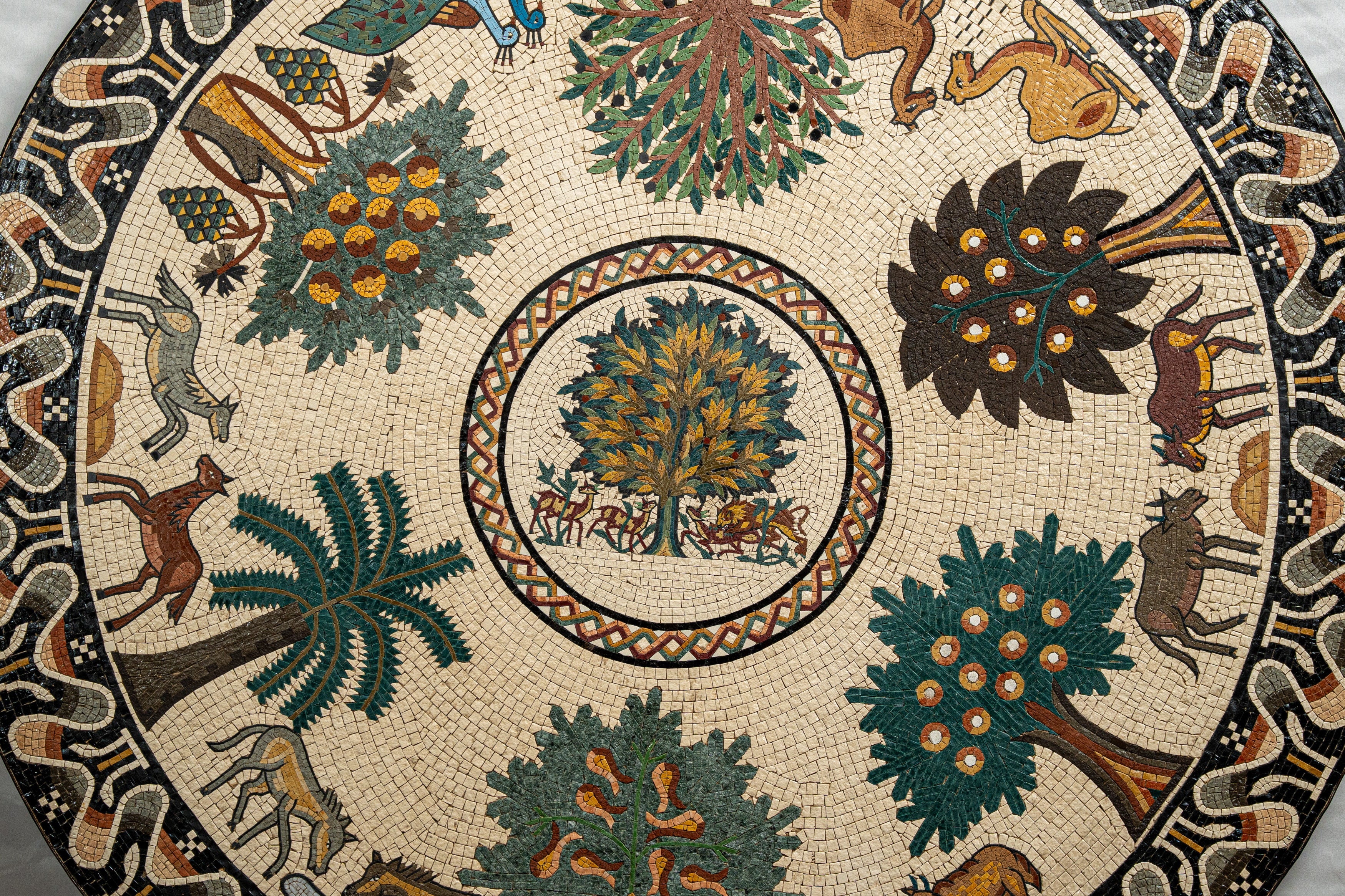 Intricate mosaic table featuring a vibrant design of trees and animals in earthy tones, showcasing artistic craftsmanship.