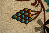 Intricate mosaic tile design featuring green and orange geometric shapes set against a textured beige background