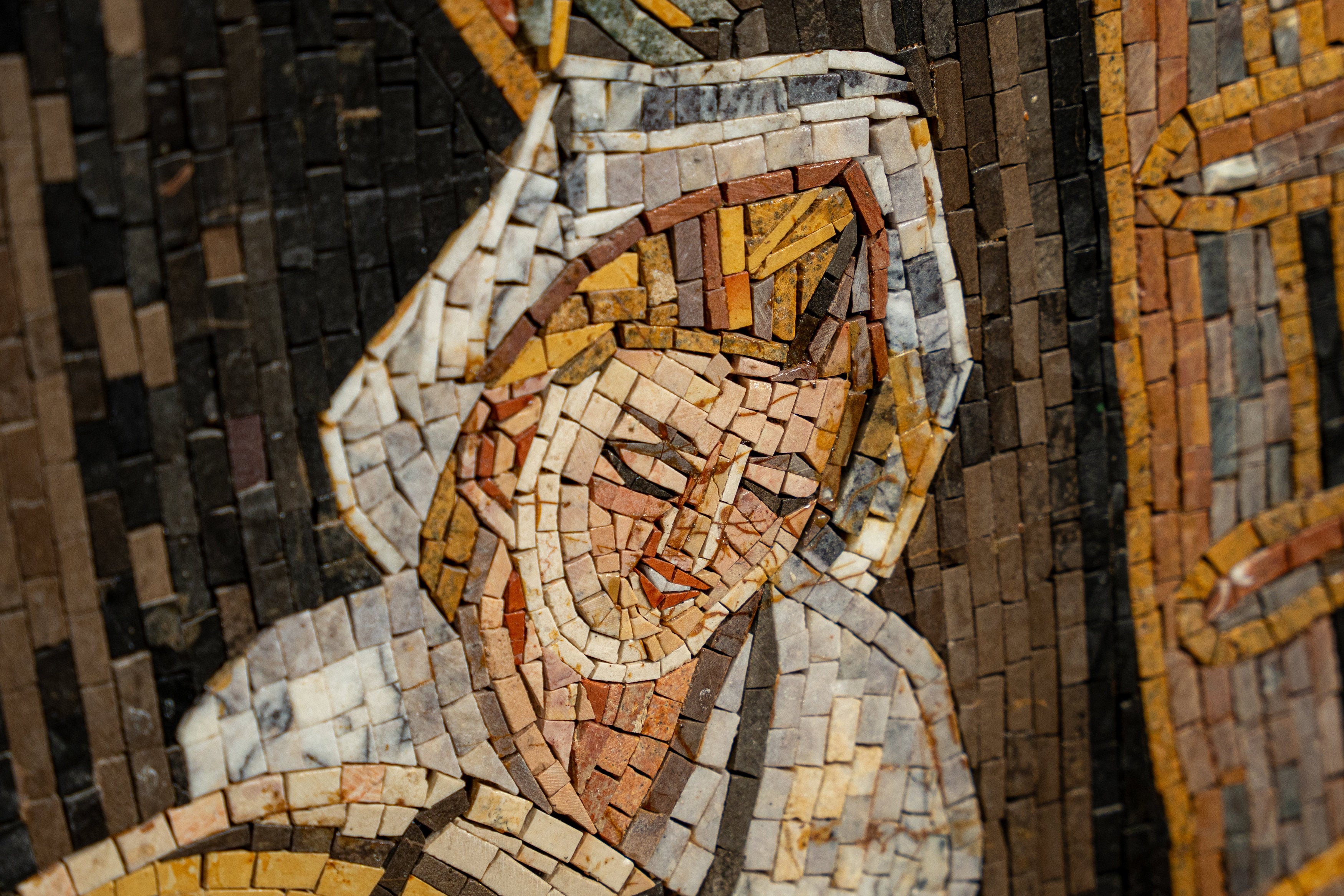 Intricate mosaic art featuring a serene figure with warm tones and textured tiles, showcasing detailed craftsmanship.