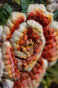 Intricate mosaic art featuring vibrant red, orange, and green tiles — a stunning display of craftsmanship and texture.