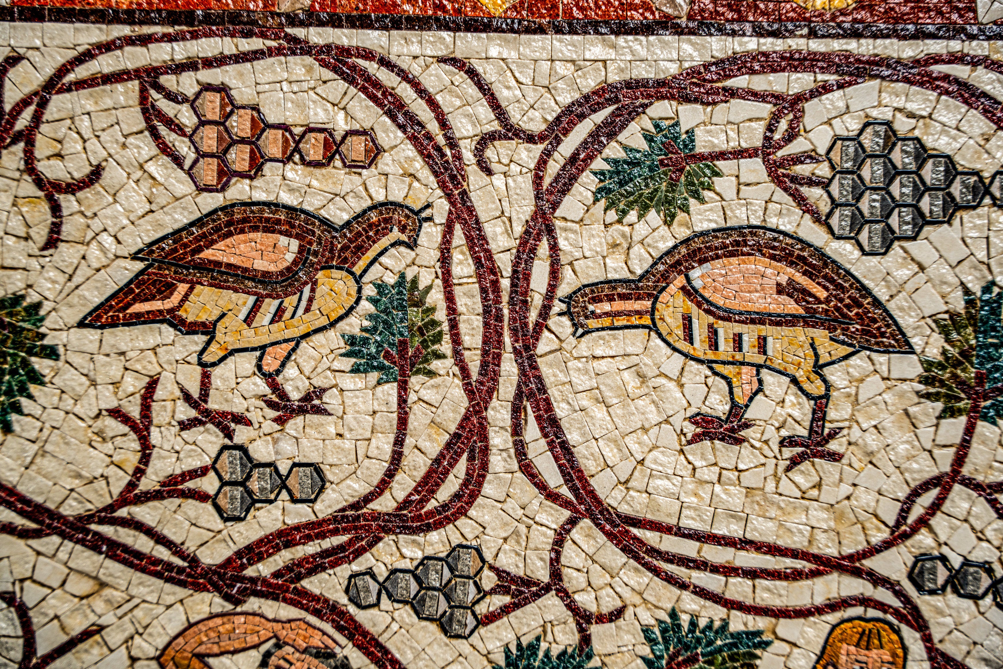 Intricate mosaic featuring colorful birds surrounded by vines and grapes — a detailed representation of ancient artistry.