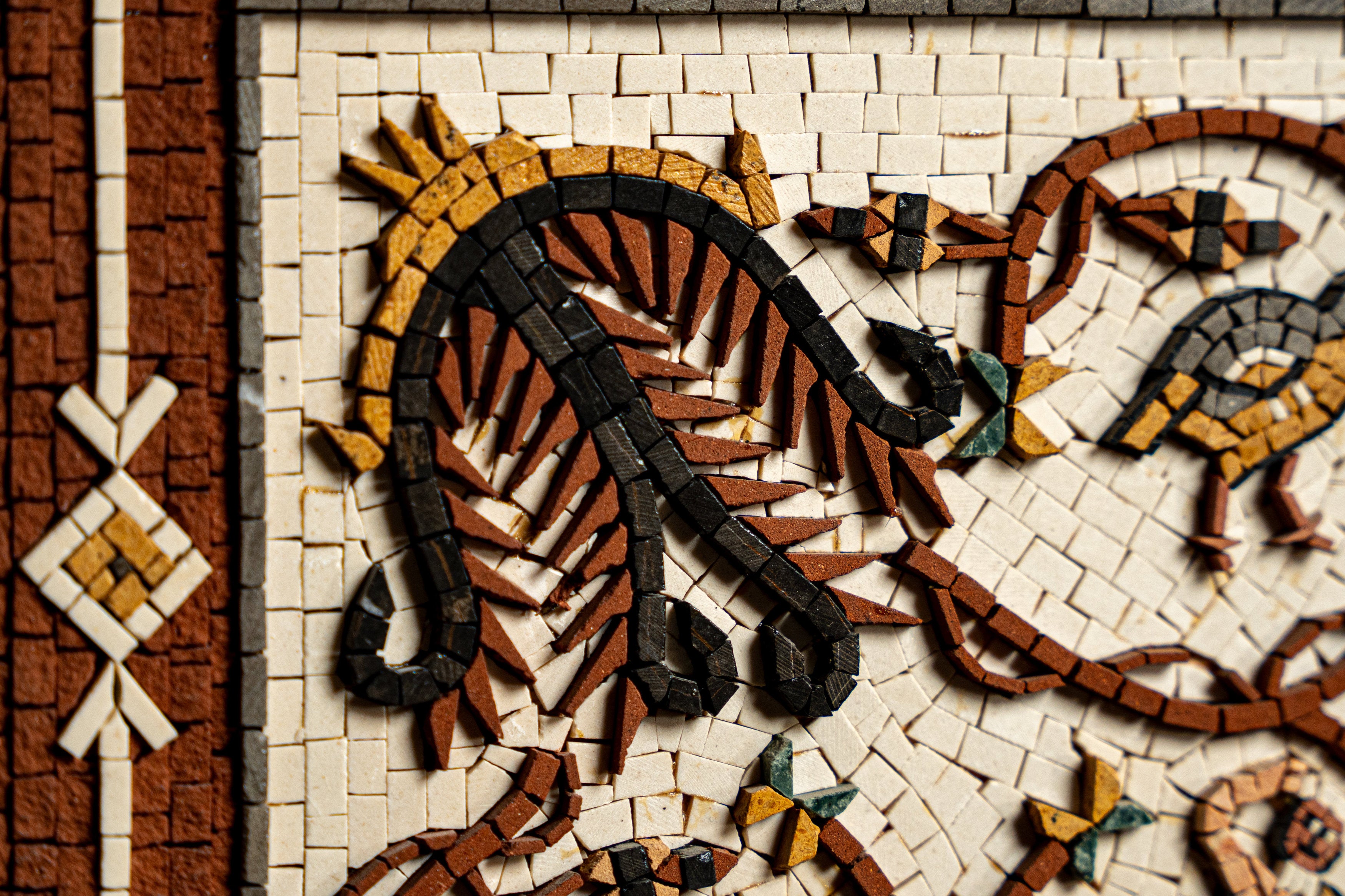 Intricate mosaic tile design featuring earthy tones of brown and black with delicate floral patterns and textured finishes