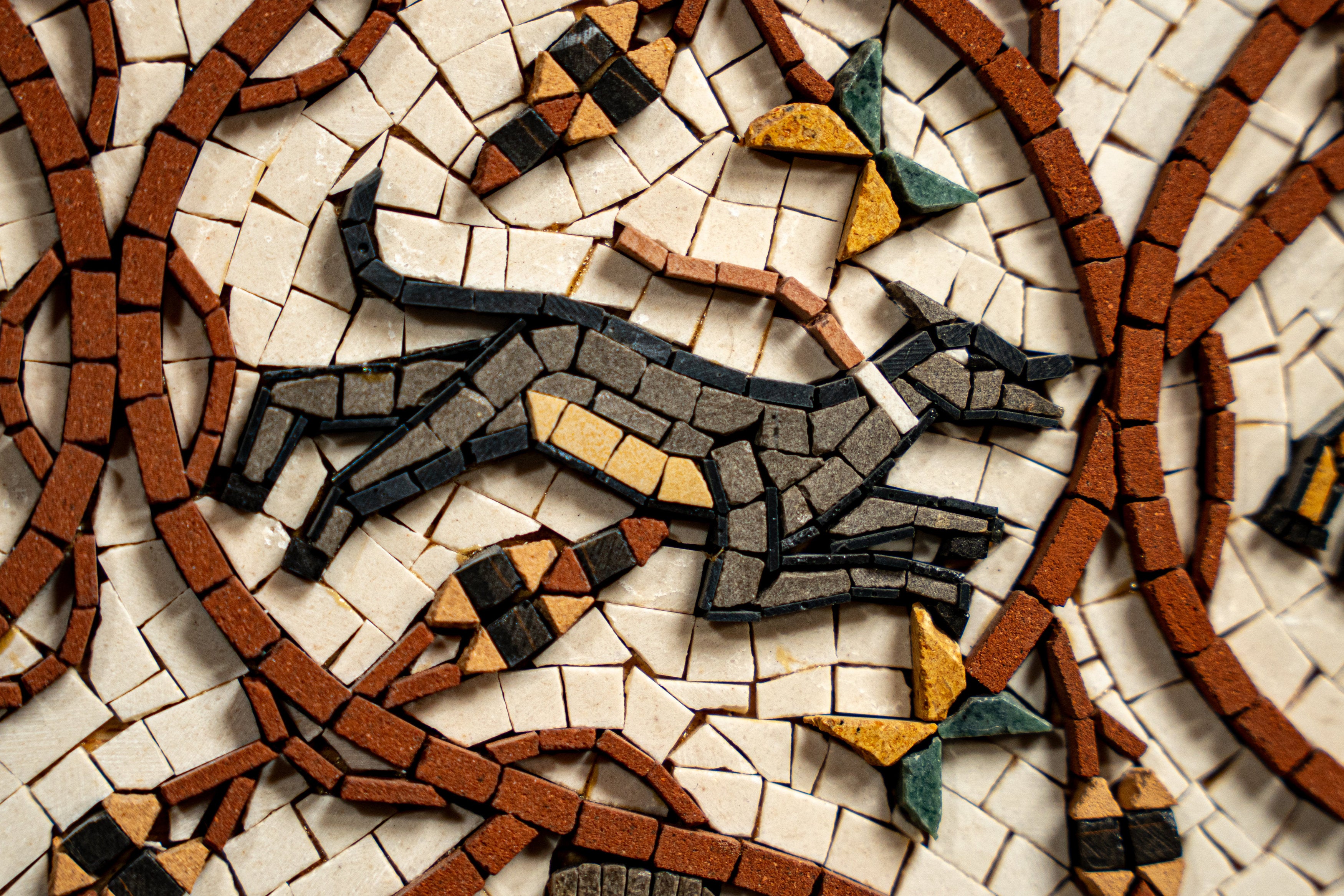 Intricate mosaic artwork featuring a running dog, crafted from colorful tiles in earthy tones and textured finishes.
