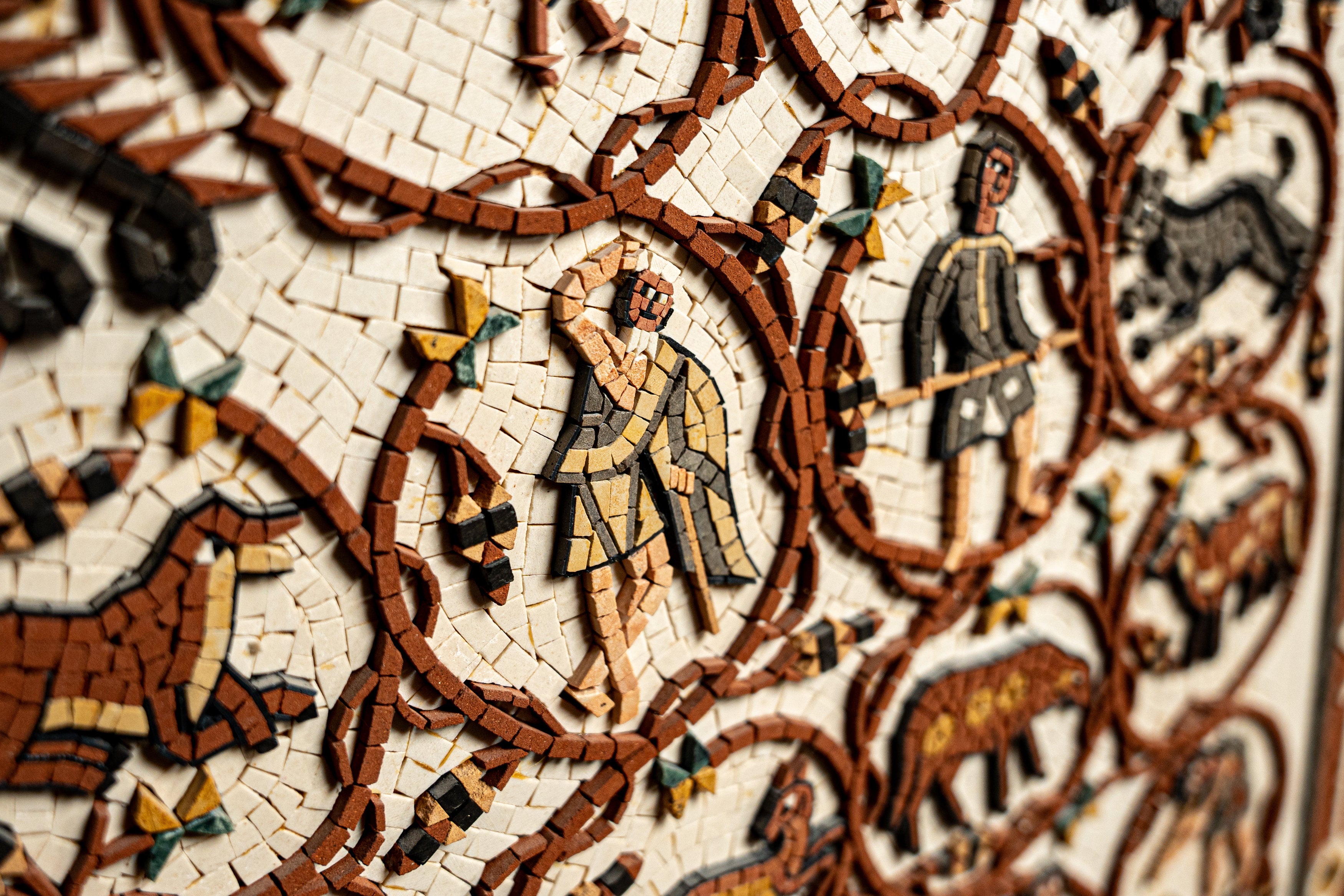 Intricate mosaic wall art featuring colorful figures and animals — showcasing detailed craftsmanship and historical themes.