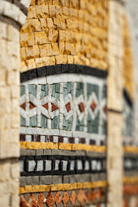 Intricate mosaic art featuring vibrant orange, green, and gray tiles — a stunning display of craftsmanship and detail.