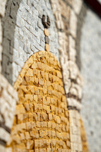 Intricate mosaic art piece featuring textured tiles in shades of gold and gray — showcasing detailed craftsmanship and depth.