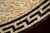 Intricate mosaic artwork featuring a blend of cream and dark tiles — showcasing a geometric pattern with textured surfaces.