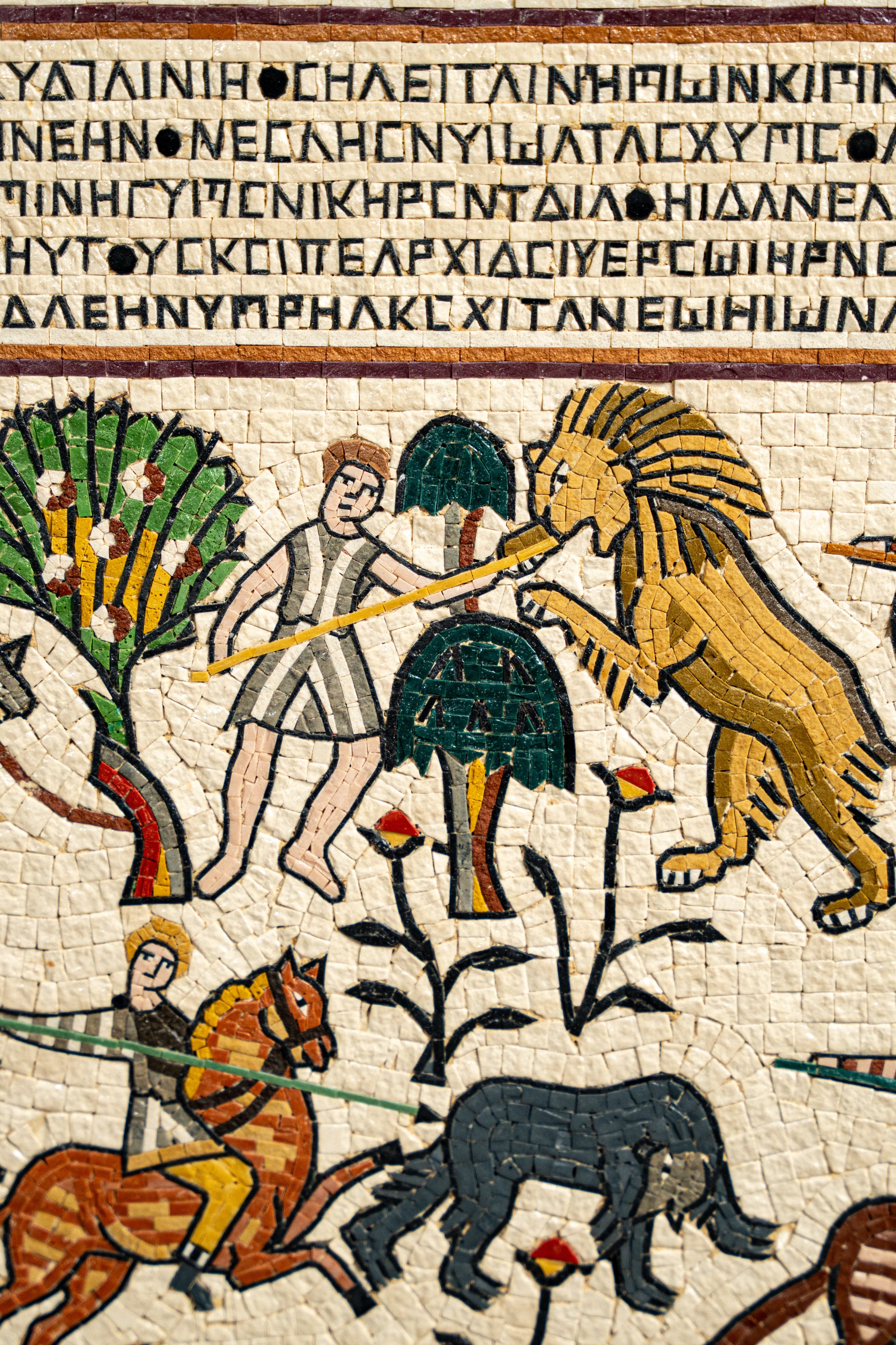 Intricate mosaic artwork depicting a lion confronting a hunter amidst vibrant trees and animals, showcasing ancient craftsmanship.