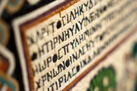 Intricate tapestry featuring ancient script on textured fabric — a rich display of historical artistry and craftsmanship.