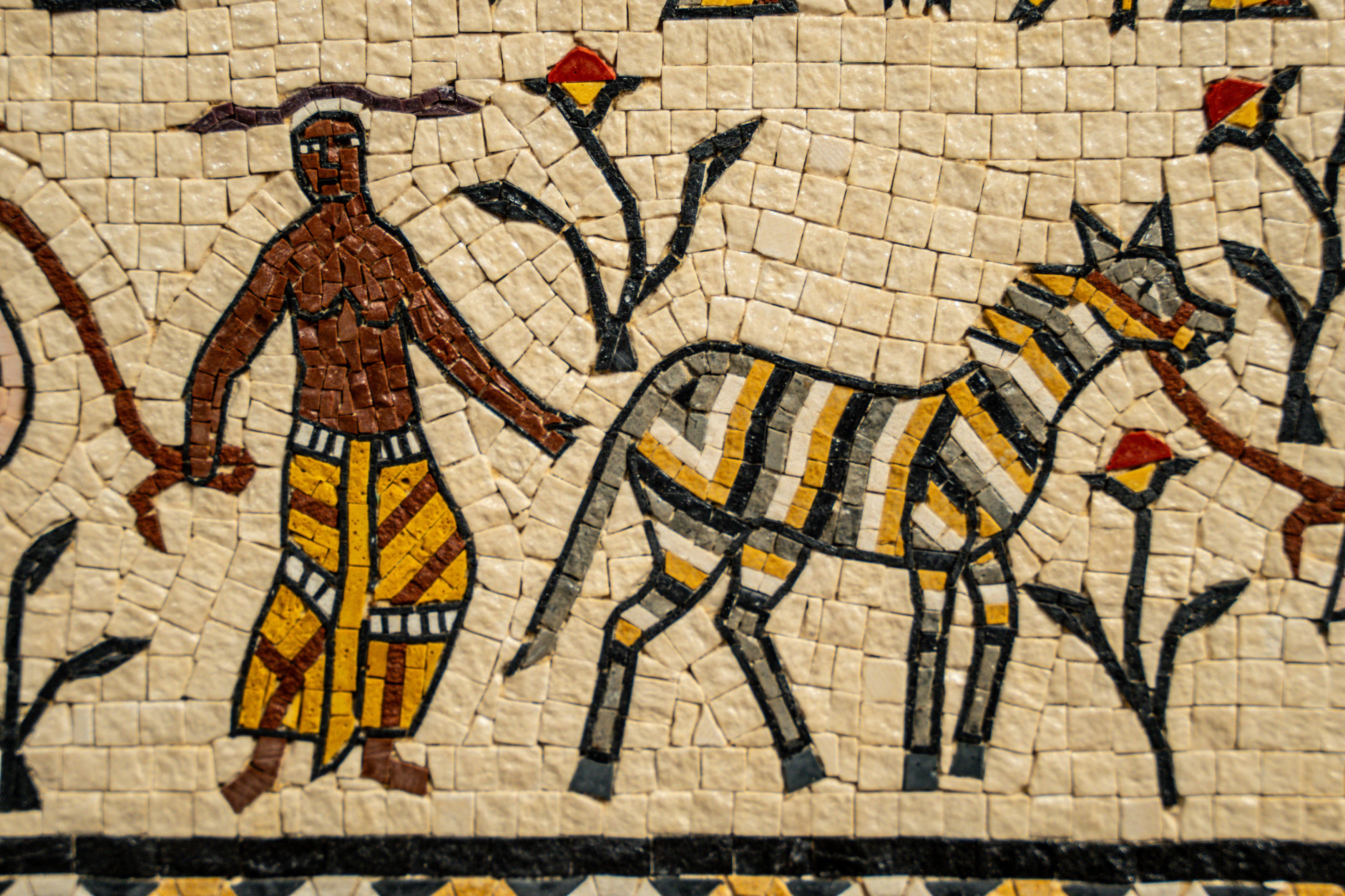 Intricate mosaic artwork featuring a figure with a patterned garment beside a striped animal — vibrant colors and detailed craftsmanship